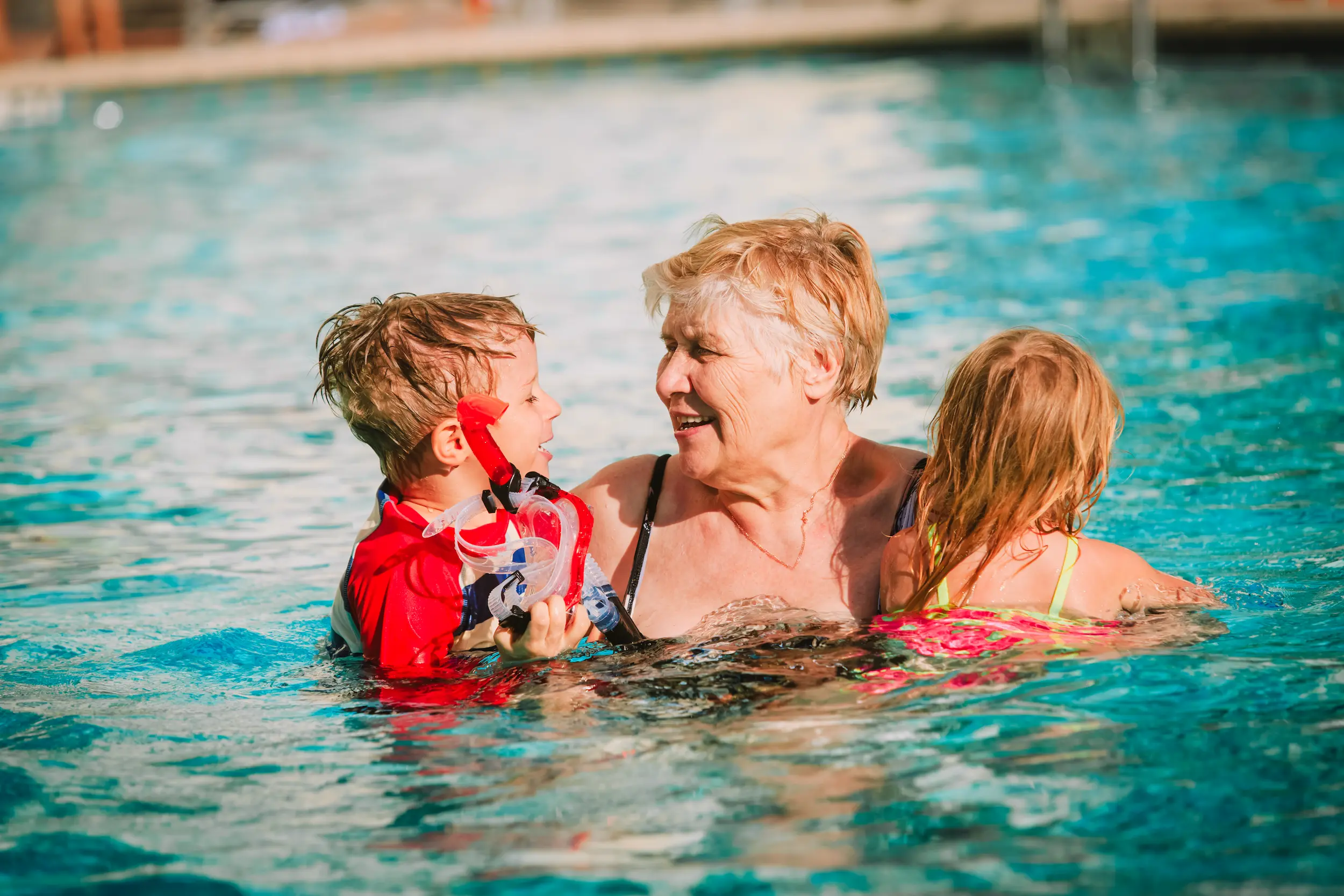 Grandmother swimming in a pool with her grandchildren